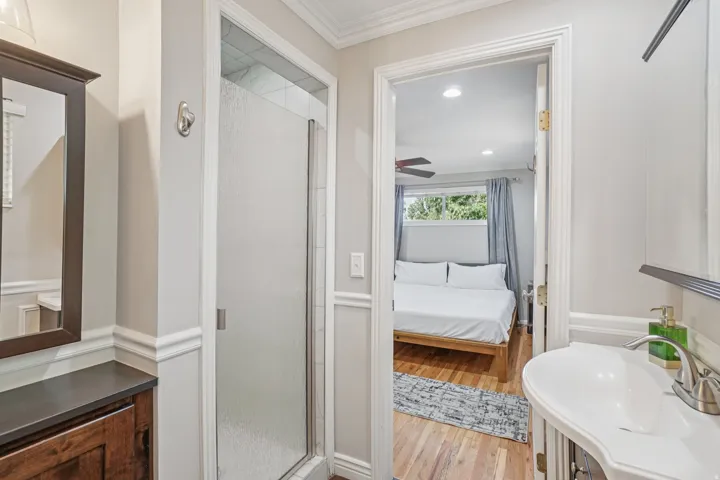 Frosted glass shower enclosure, wood-finish flooring, recessed lighting, ceiling fan, and window