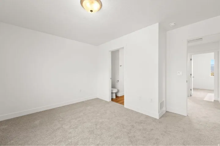 Neutral carpet flooring in a bright room with white walls and a ceiling-mounted light fixture