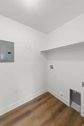 Laundry area featuring wood-finish flooring, white walls, built-in shelving, and utility hookups