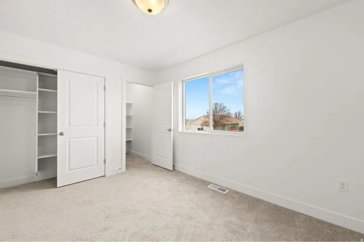 Carpeted room featuring a double-door closet with shelving, a single window, and a flush-mount ceiling light