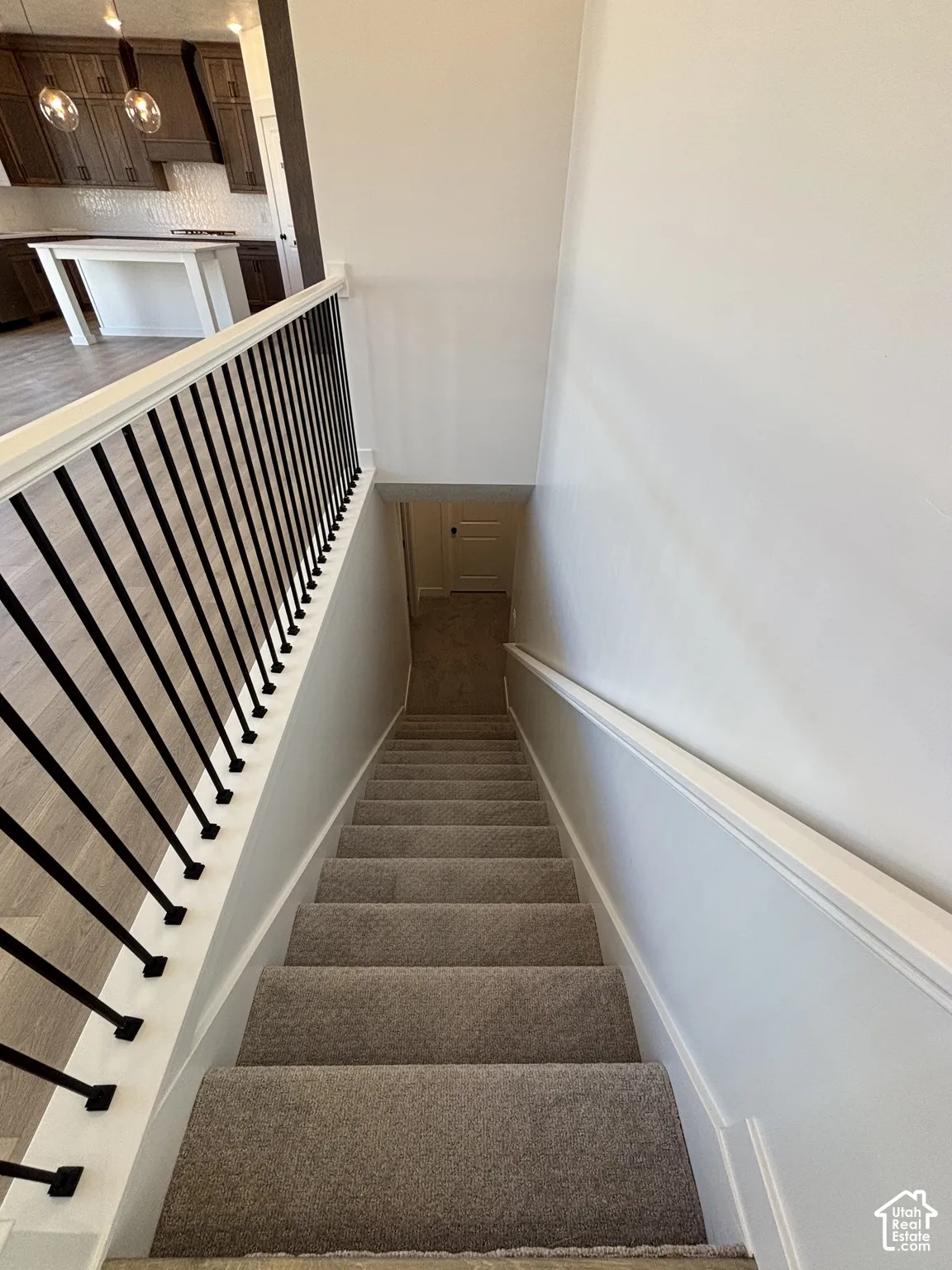 Carpeted staircase with white trim and a black metal baluster railing