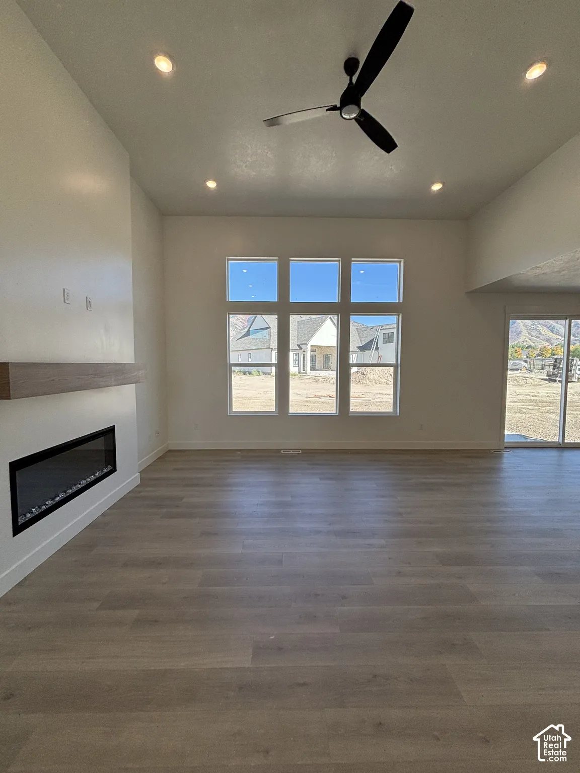 Spacious room with wood-finish flooring, a contemporary linear fireplace with a floating mantel, and a multi-panel window array