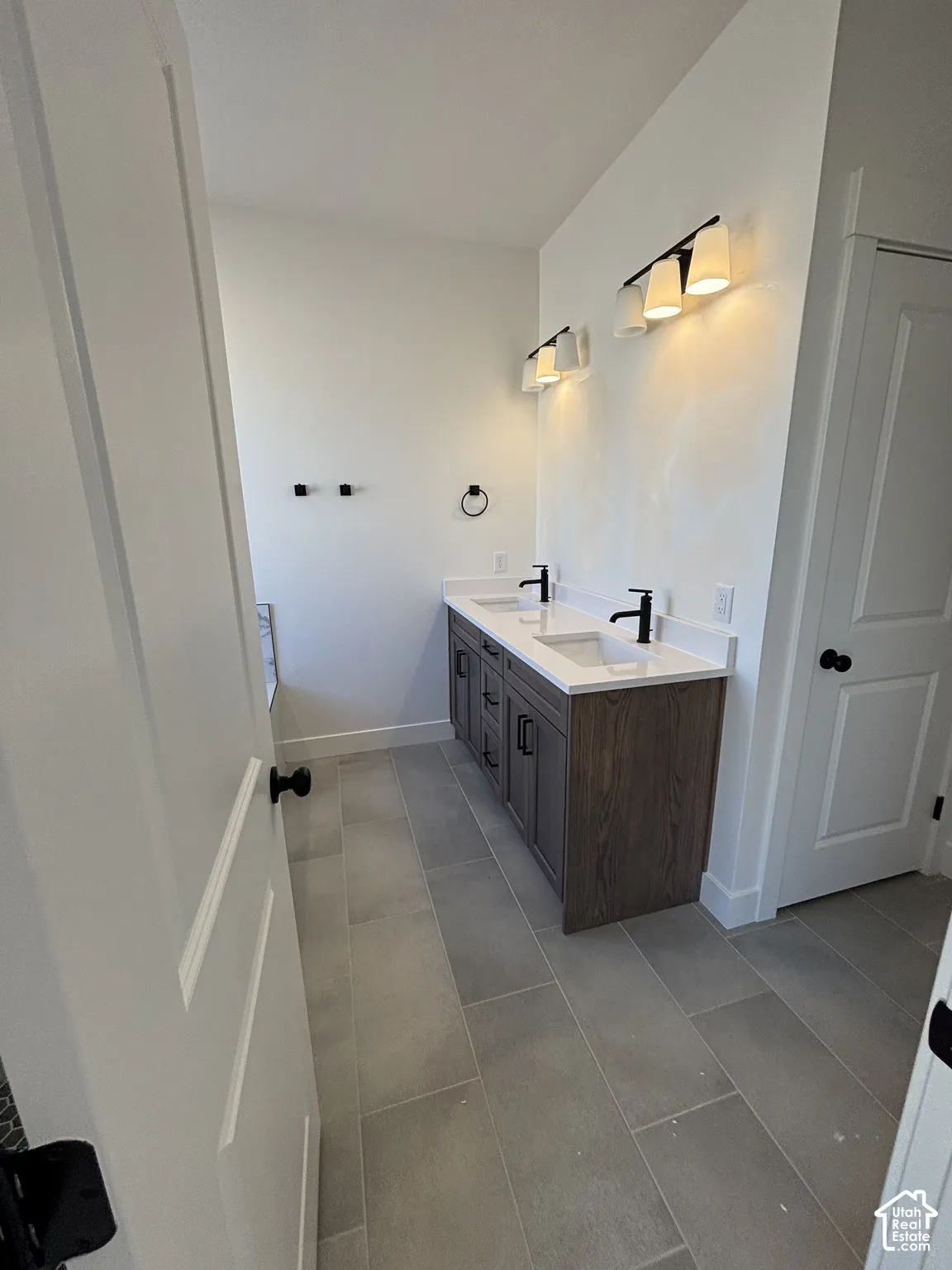 Dual vanity with a wood-finish cabinet, white countertops, and matte black fixtures