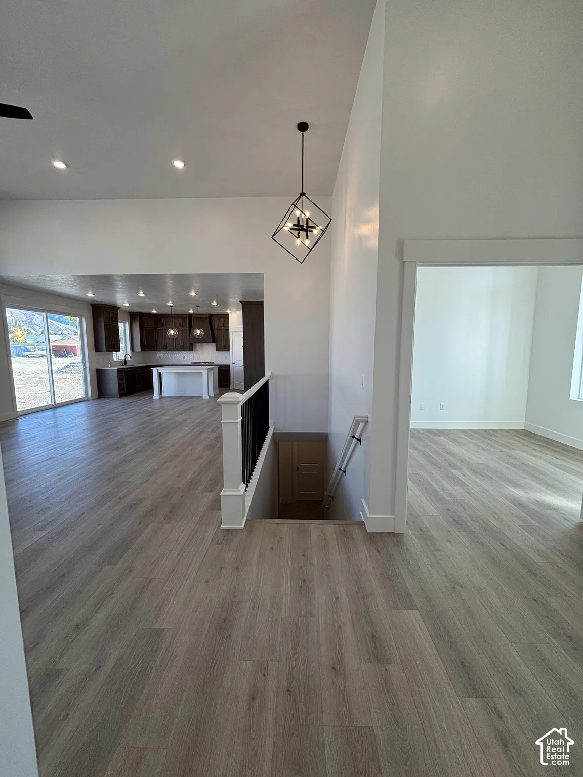 Open-concept layout featuring wood-finish flooring, a modern geometric chandelier, and recessed lighting