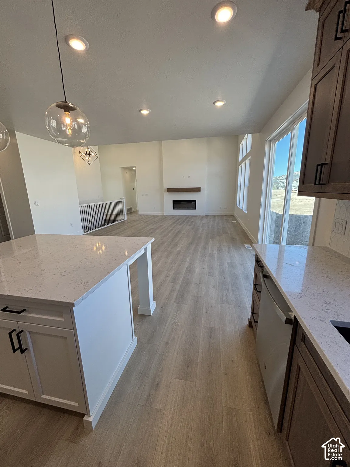 Open-concept living area with wood-finish flooring, recessed lighting, and a modern fireplace