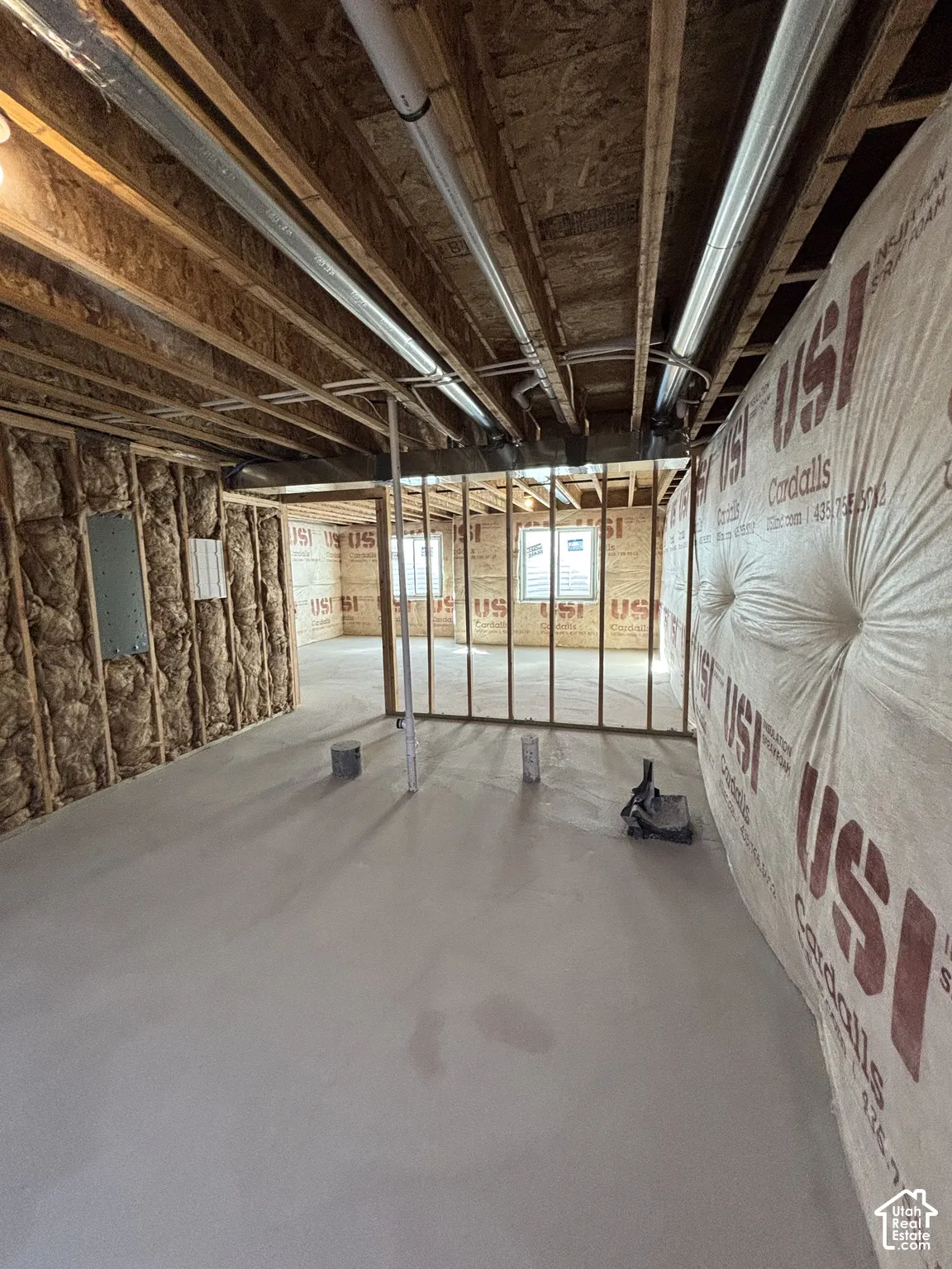 Unfinished lower level featuring concrete flooring, exposed wood joists, and wall insulation
