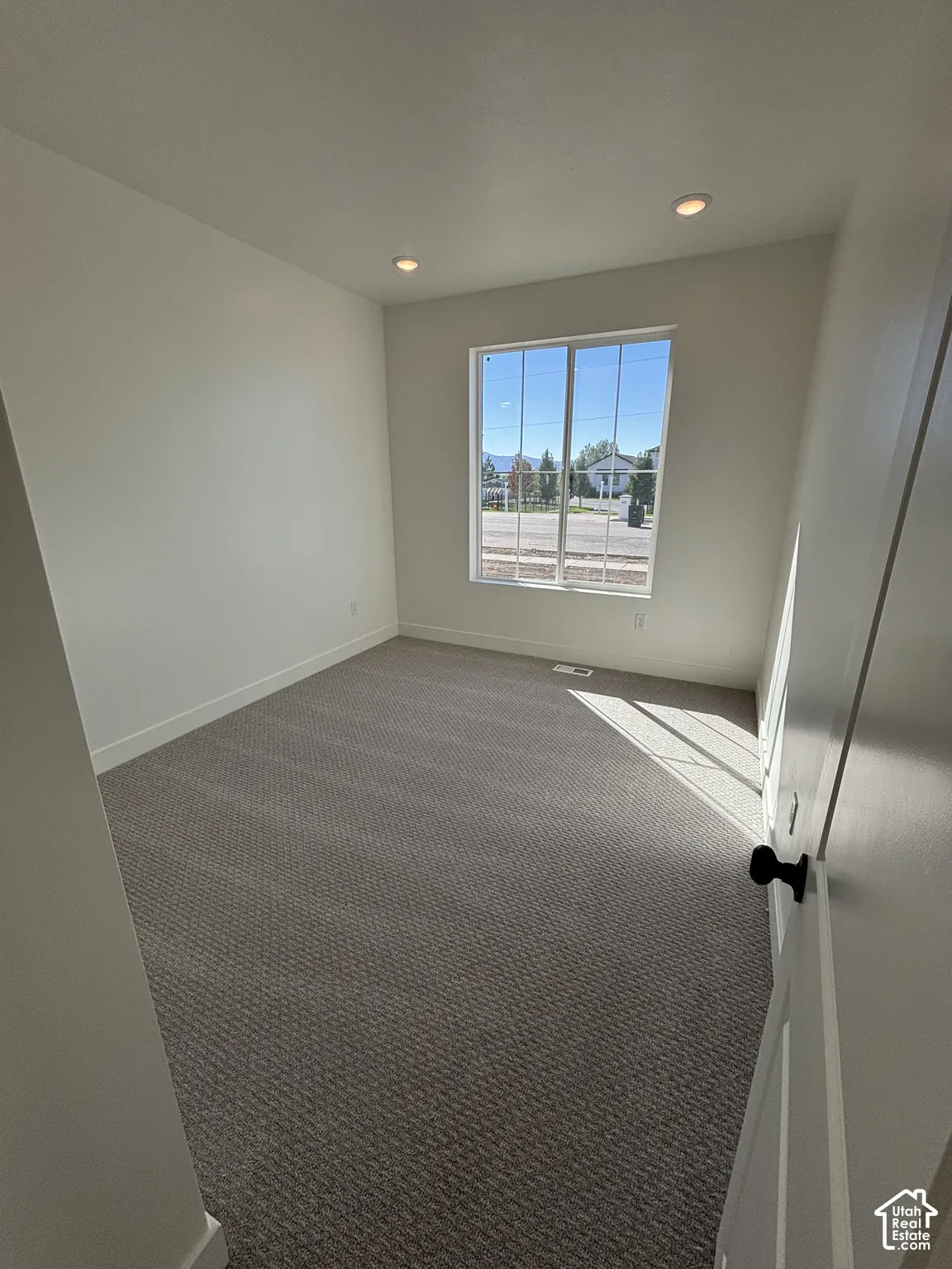 Recessed lighting illuminates this room, featuring light-colored walls and patterned carpeting