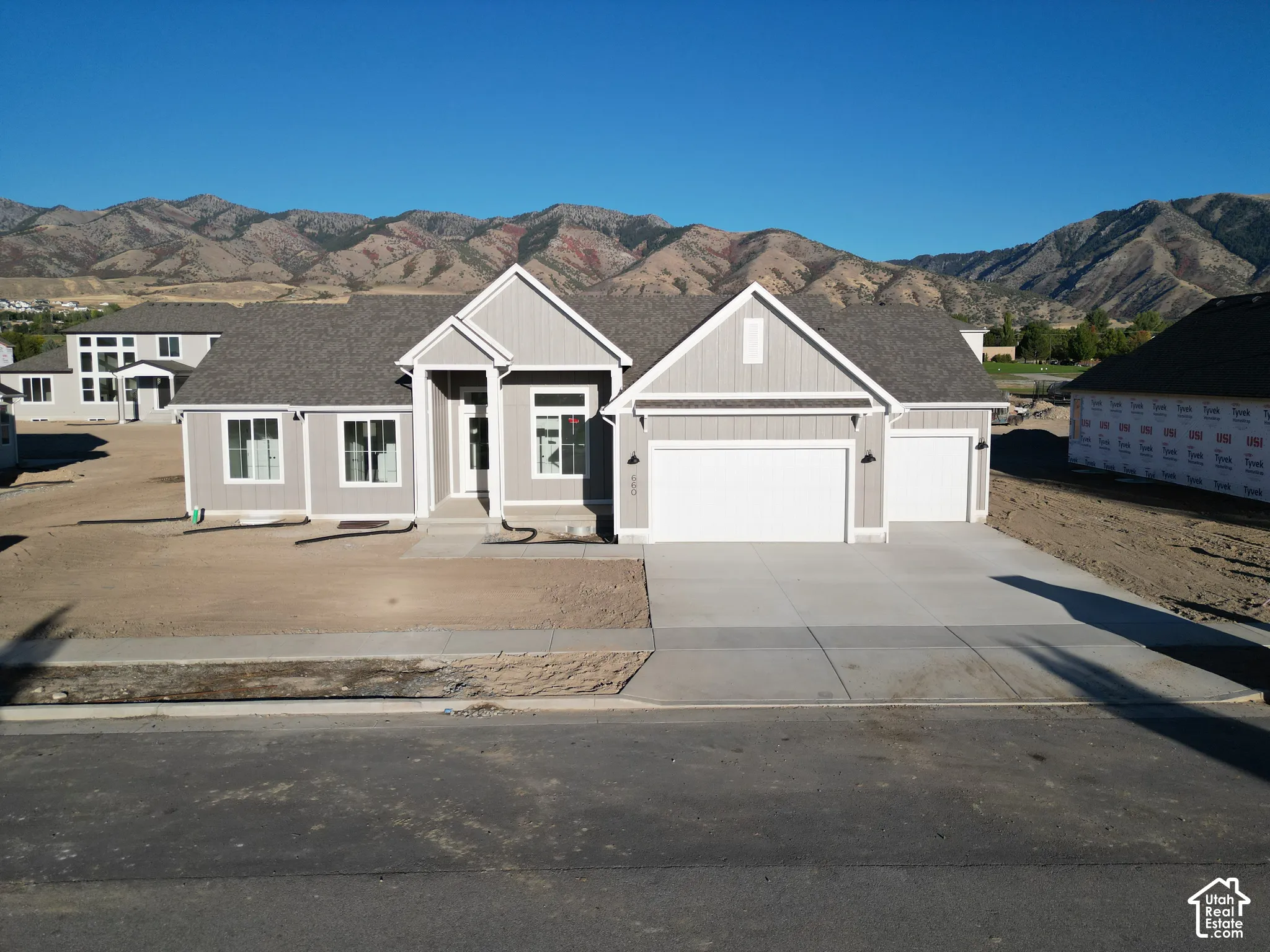 Contemporary ranch-style exterior with a gabled roofline, light gray siding, an attached two-car garage, an additional attached one-car garage, and a concrete driveway