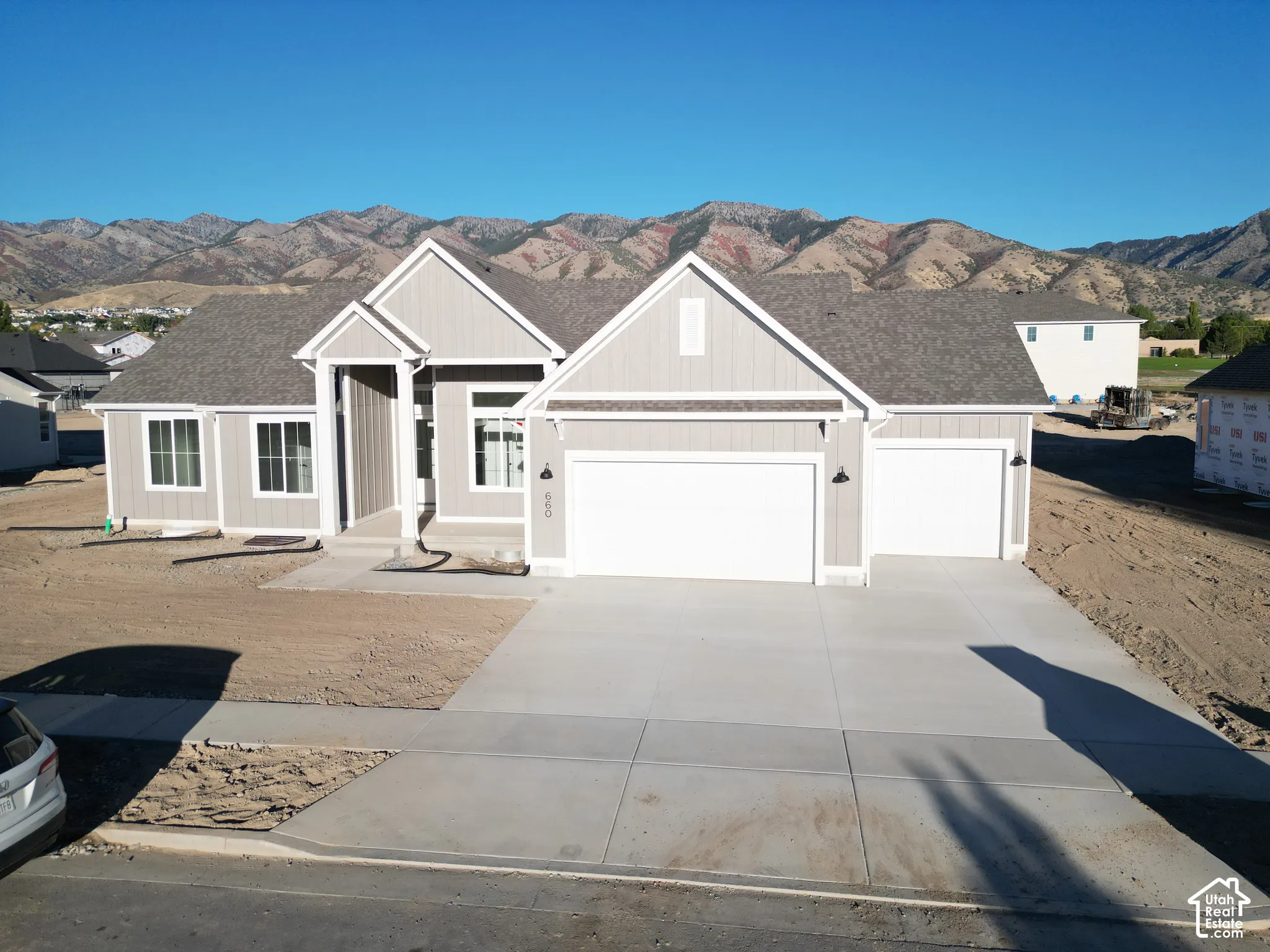 Light gray siding exterior with white trim, a dark gray shingle roof, and a prominent mountain backdrop