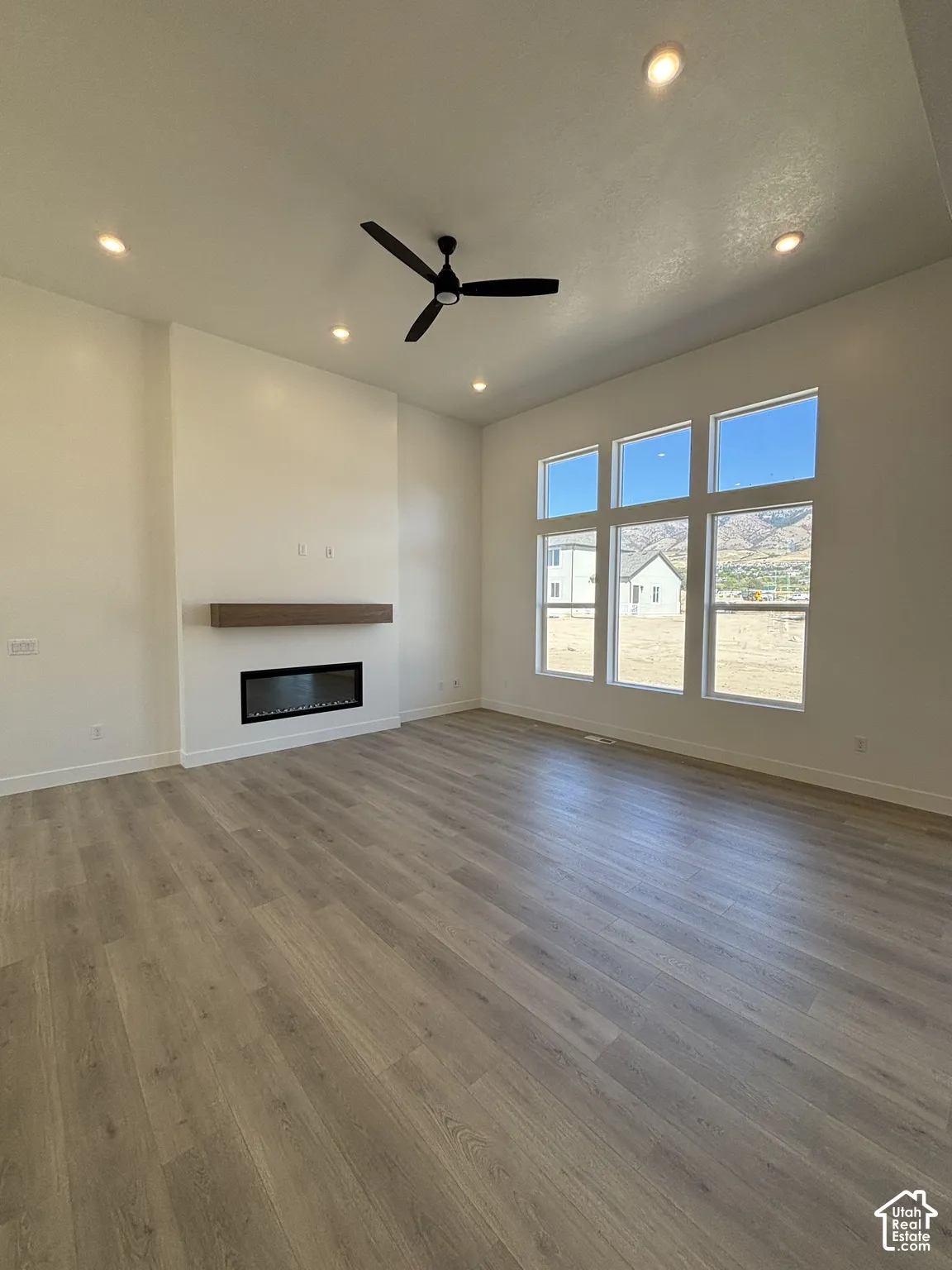 Spacious room featuring wood-finish flooring, recessed lighting, and a contemporary ceiling fan
