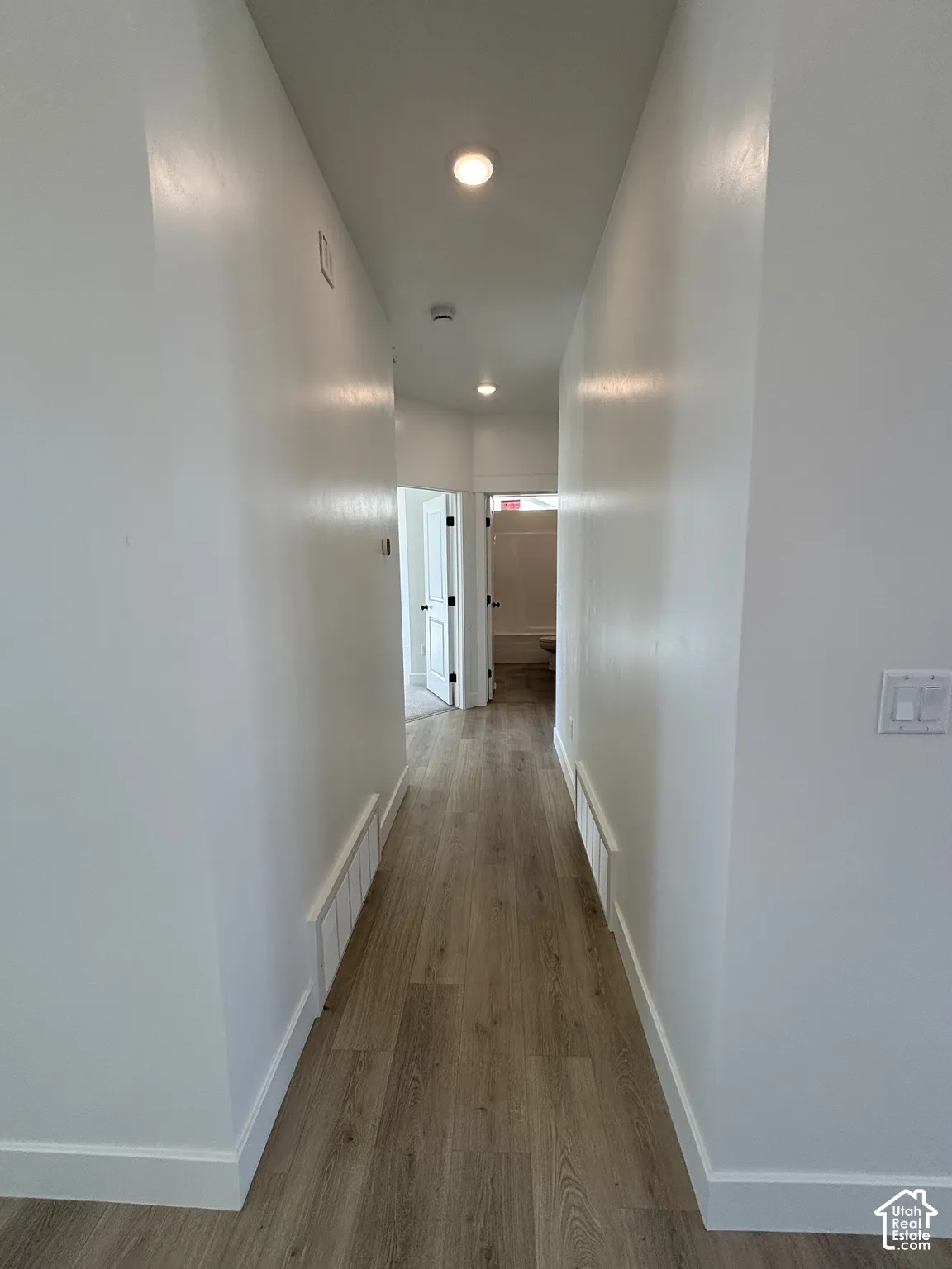 Wood-finish flooring with white baseboards and painted walls