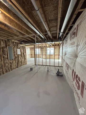 Unfinished lower level featuring concrete flooring, exposed wood joists, and wall insulation