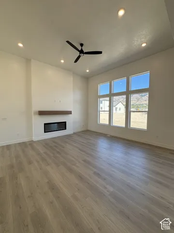 Spacious room featuring wood-finish flooring, recessed lighting, and a contemporary ceiling fan