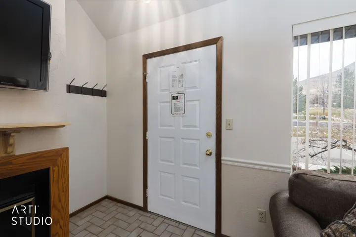 Entry featuring a white door with wood-finish trim, tile flooring, and a large window with vertical blinds
