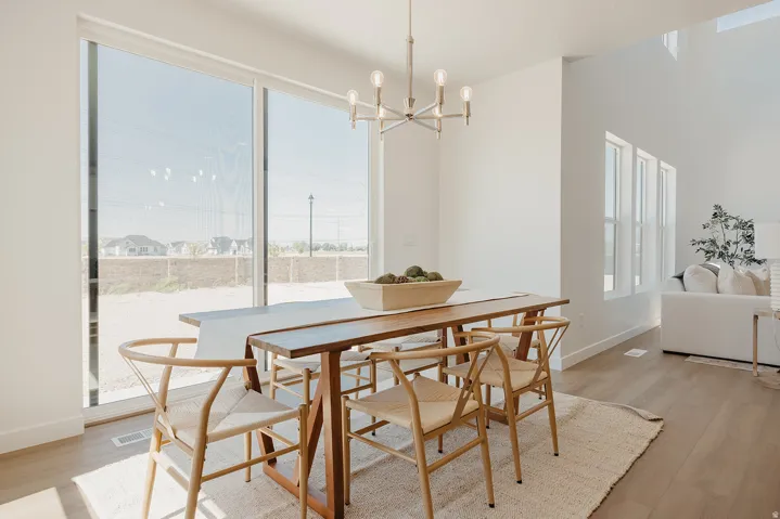 Spacious dining area featuring a modern linear chandelier, expansive sliding glass door, and wood-finish flooring
