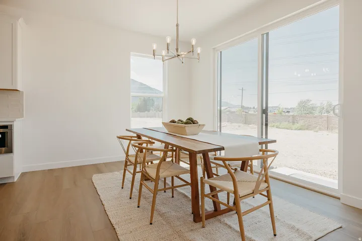 Hardwood-finish flooring, white walls, large sliding glass door, single fixed window, and a modern chandelier