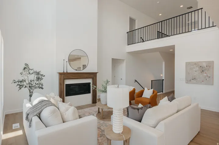 Living area featuring soaring ceilings, a wood-surround fireplace with a tiled hearth, and light wood-finish flooring