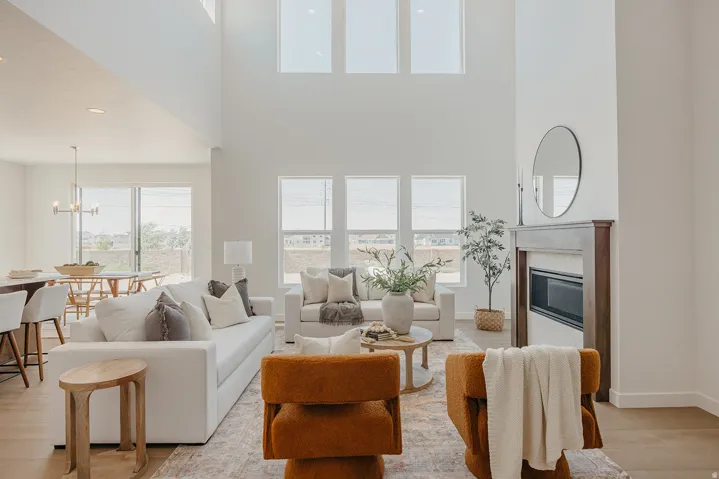 Spacious living area featuring high ceilings, wood-finish flooring, a contemporary fireplace, large windows, and an open-concept dining space