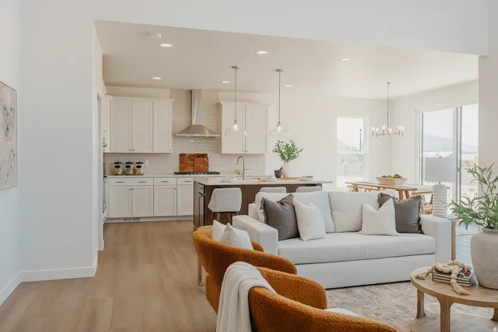 Open-concept living area featuring wood-finish flooring, recessed lighting, and a kitchen with white cabinetry and stainless steel range hood