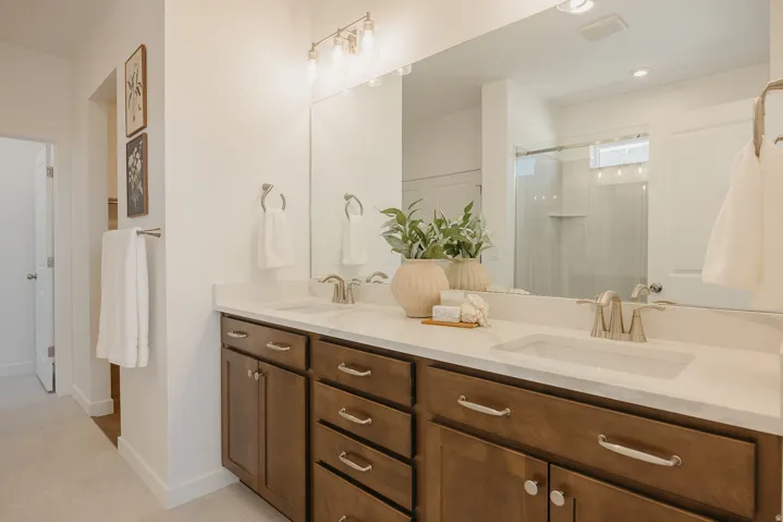 Dual vanity with integrated sinks, brushed nickel fixtures, white countertop, and a large mirror