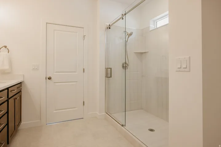 Glass-enclosed shower with a transom window, wall-mounted showerhead, and integrated shelving