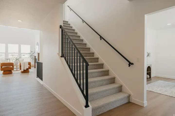Staircase featuring carpeted treads and risers with a black metal handrail and balusters
