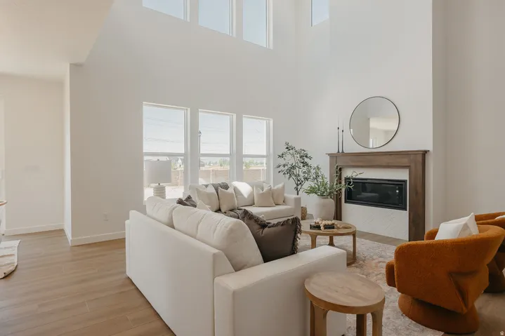 Vaulted ceilings with high windows, wood-finish flooring, a built-in fireplace with a wood mantel, and multiple large windows