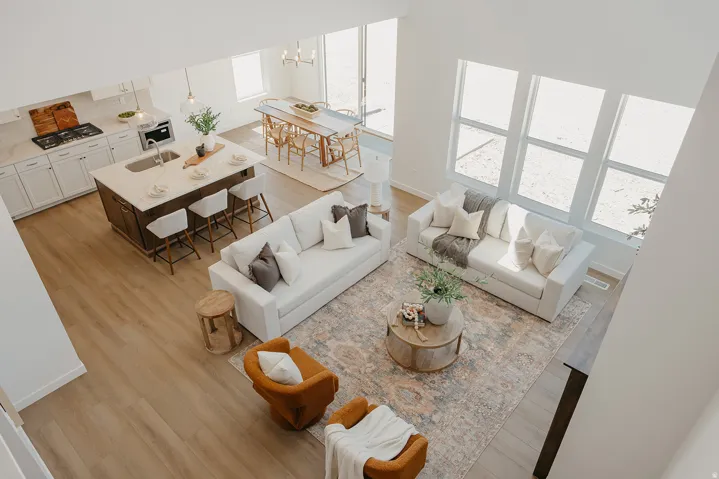 Open-concept living area with high ceilings, wood-finish flooring, a kitchen island with seating, a gas range, and large windows