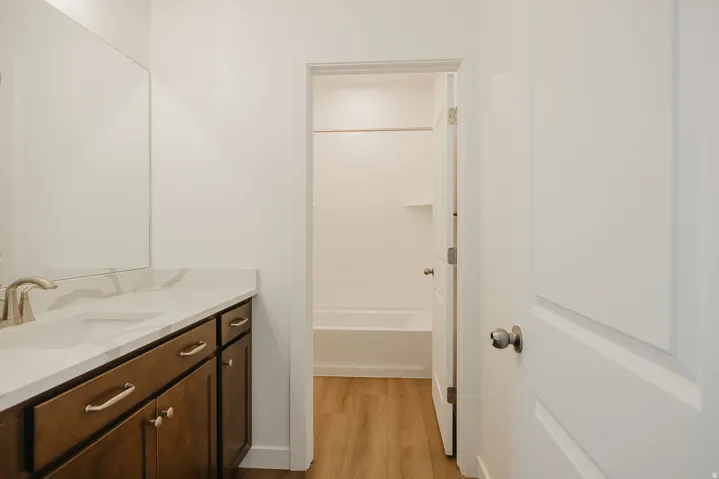 Bathroom vanity featuring a single basin sink, white countertop, dark wood-finish cabinetry, and brushed nickel fixtures