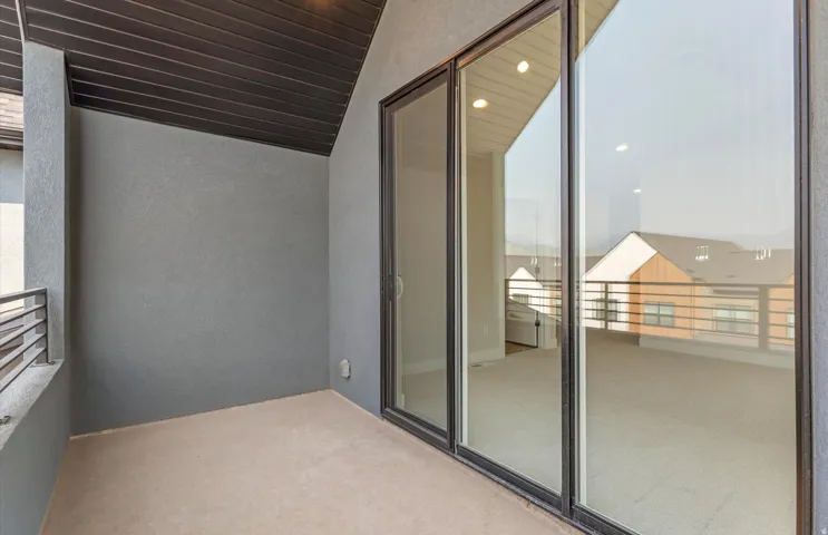 Balcony off loft with a textured exterior wall, dark wood-finish ceiling, and a metal railing