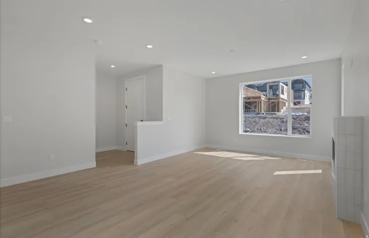Recessed lighting, wood-finish flooring, and a window provide natural illumination