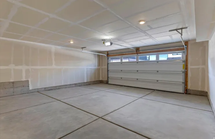 Concrete flooring, garage door with upper window panels, and ceiling-mounted lighting