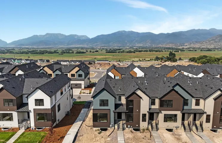 Aerial perspective of a developing residential community with multi-level homes, dark shingle roofs, and varied exterior siding