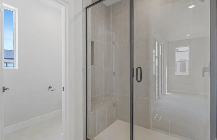 Enclosed shower with a glass door, tiled walls, and a built-in bench