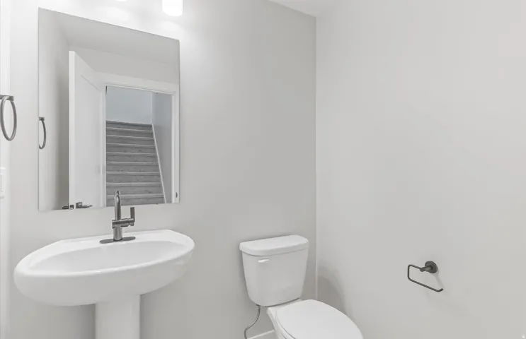 Pedestal sink with a single-handle faucet, rectangular mirror, and a wall-mounted light fixture