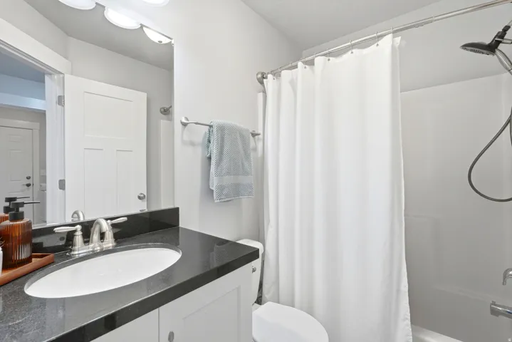 Upstairs hall full bath with white vanity with granite countertop, undermount sink, and brushed nickel faucet