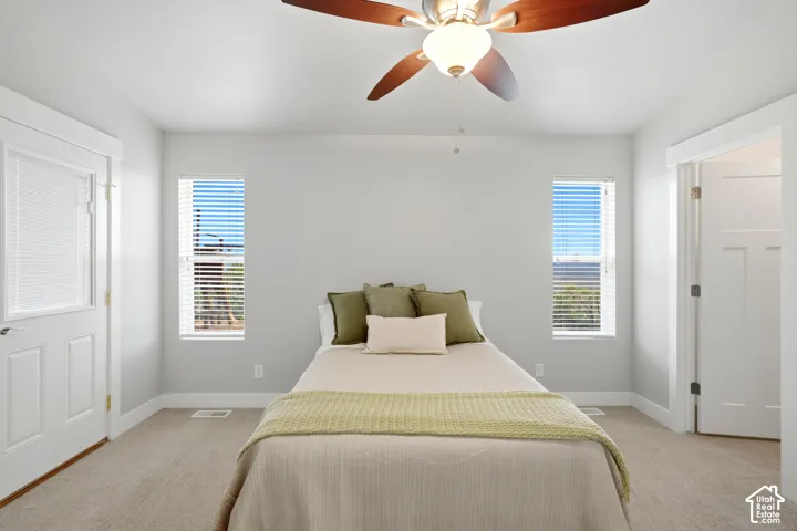 Recessed windows with blinds, carpeted flooring, white interior doors, and a ceiling fan with integrated lighting