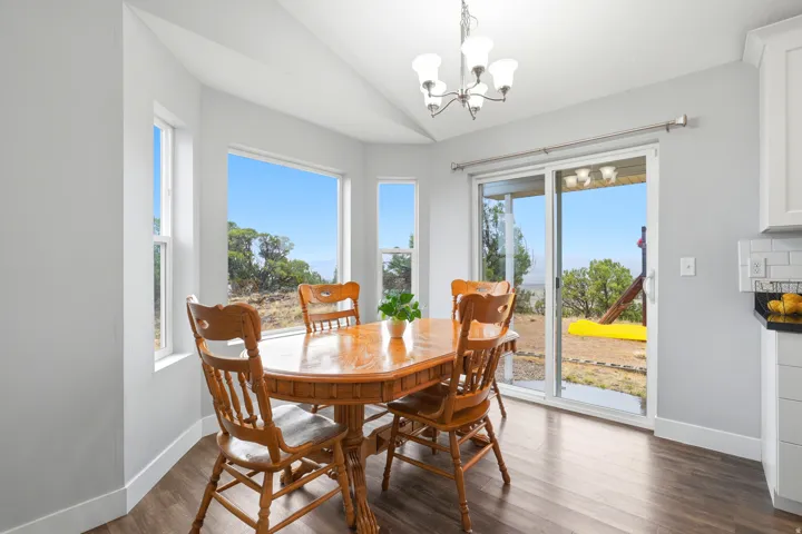 Vaulted ceiling, LVP, multiple windows, sliding glass door, and a chandelier with glass shades