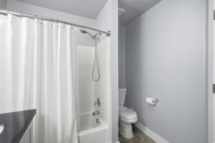 White shower/tub combination with a curved chrome shower rod and showerhead