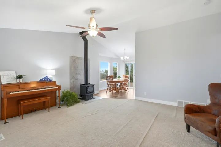 Vaulted ceiling with a ceiling fan, wood-burning stove with a stone surround