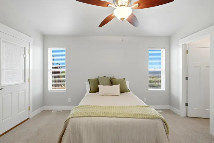 Recessed windows with blinds, carpeted flooring, white interior doors, and a ceiling fan with integrated lighting