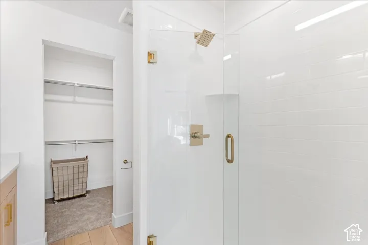 Glass-enclosed shower with a rainfall showerhead, white subway tile surround, and brushed gold fixtures
