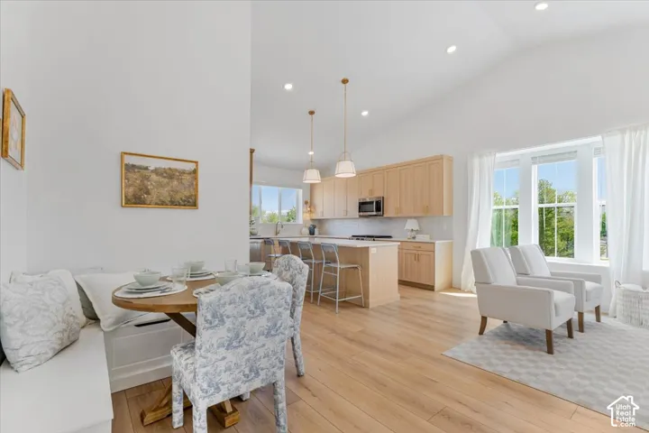 Vaulted ceilings, wood-finish flooring, kitchen island with seating, built-in banquette, and large windows