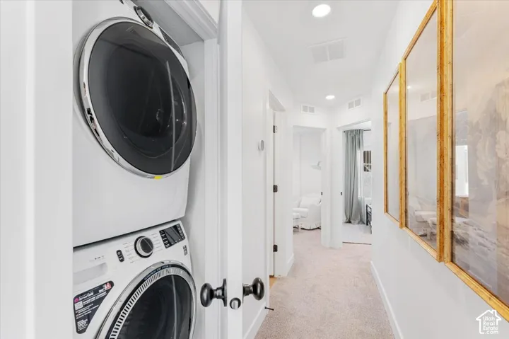 Integrated stacked laundry appliances, recessed lighting, and carpeted hallway
