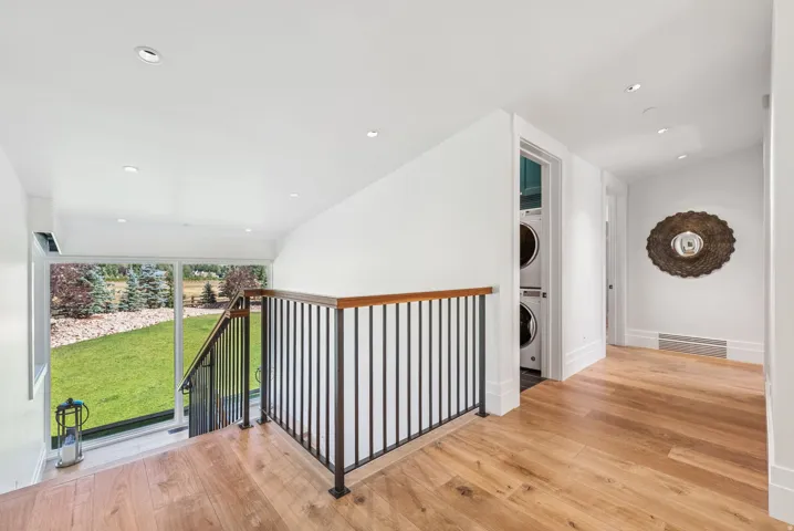 Hardwood flooring throughout this upper-level hallway featuring recessed lighting and a contemporary metal and wood staircase railing