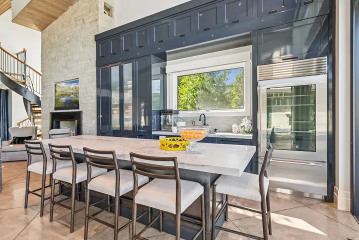 Kitchen island featuring a substantial countertop, integrated sink, and dark cabinetry