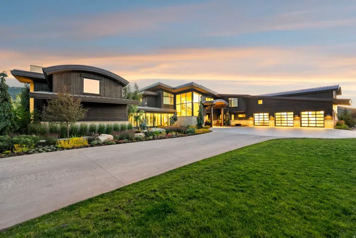 Modern architectural residence showcasing a striking curved roofline and dark exterior facade with expansive glazing