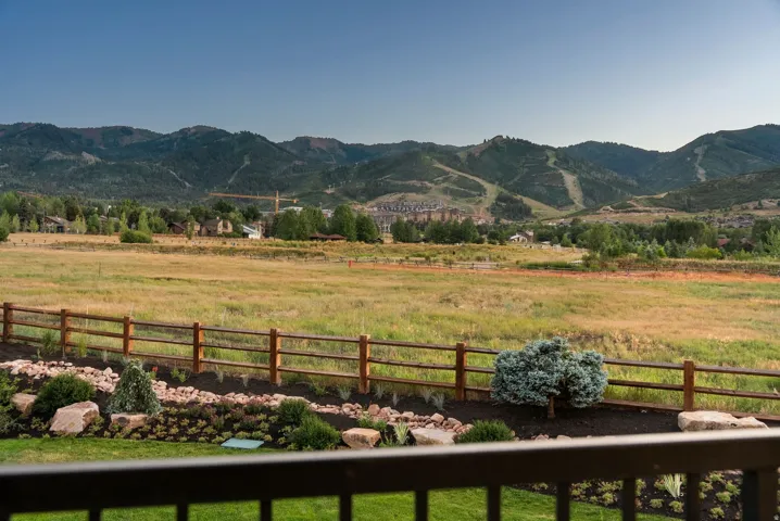 Expansive mountain scenery framing a grassy field with a wooden fence