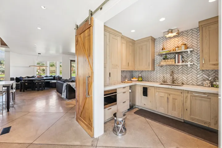 Kitchenette featuring wood-finish cabinetry, light countertops, and a herringbone tile backsplash