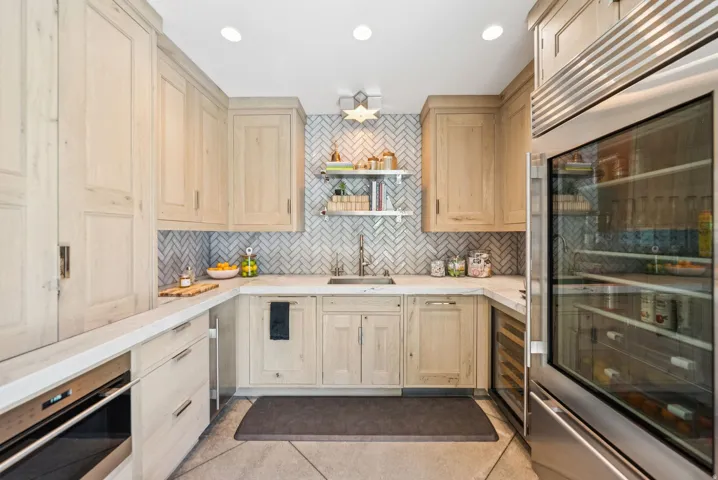 Chef's kitchen featuring light wood cabinetry with soft-close hardware, white quartz countertops, and a geometric tile backsplash